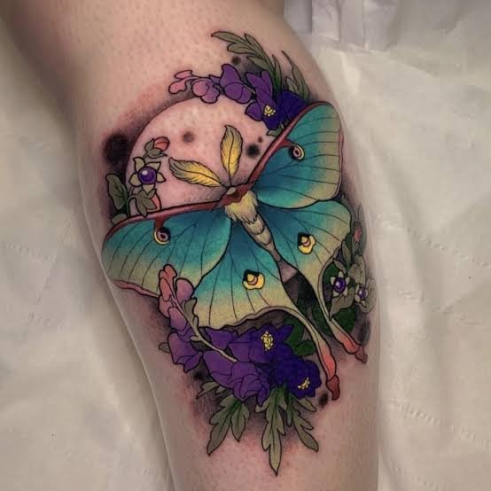 Tatuaje neotradicional de polilla con elementos florales y ornamentales.
